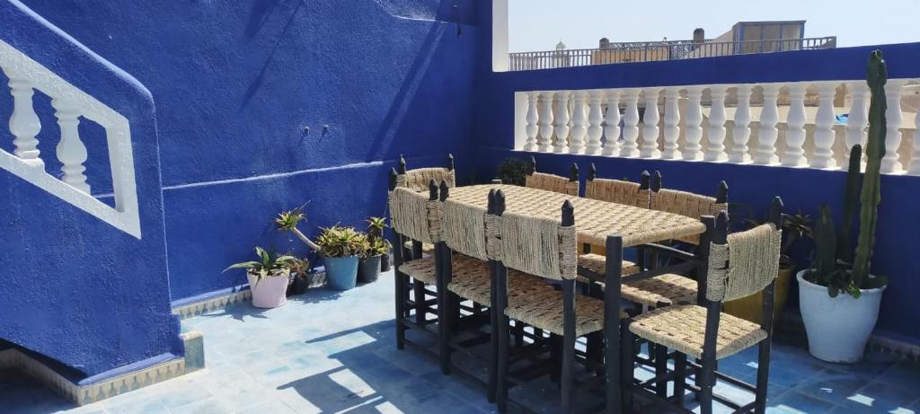 een blauwe eetkamer met een tafel en stoelen bij Dar Massaneh in Essaouira