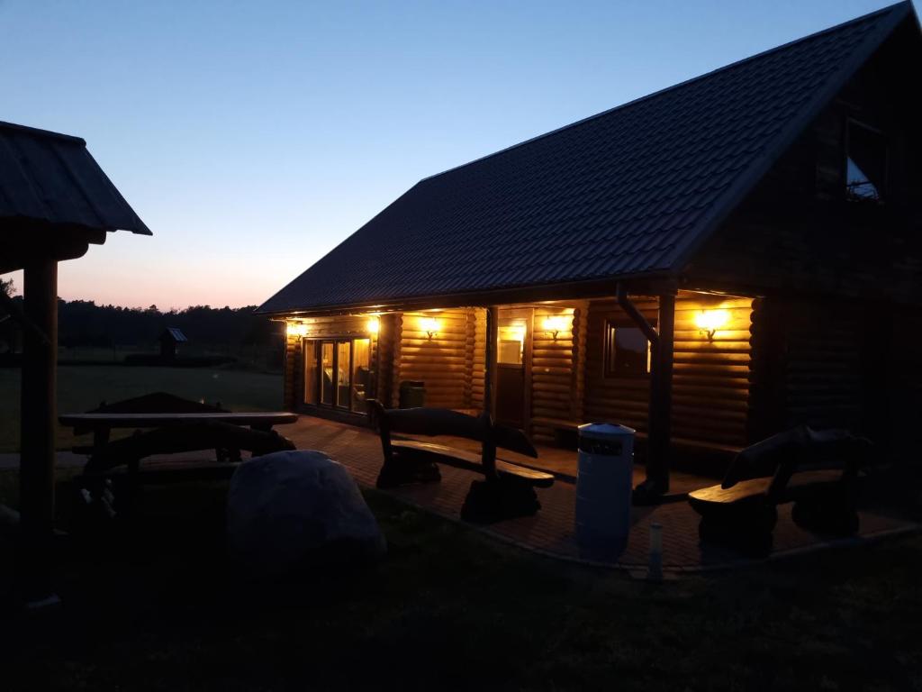 eine Blockhütte mit Licht in der Abenddämmerung in der Unterkunft Gatiņi in Ventspils