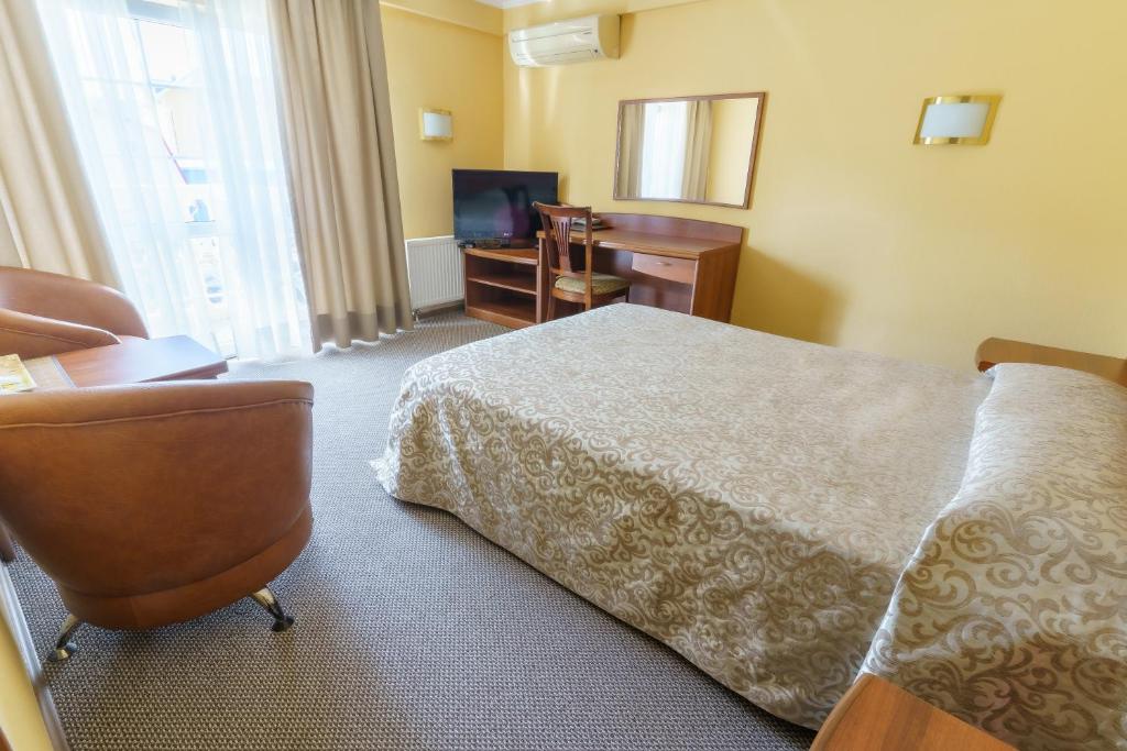 a hotel room with a bed and a desk and a television at Marina Hotel in Adler