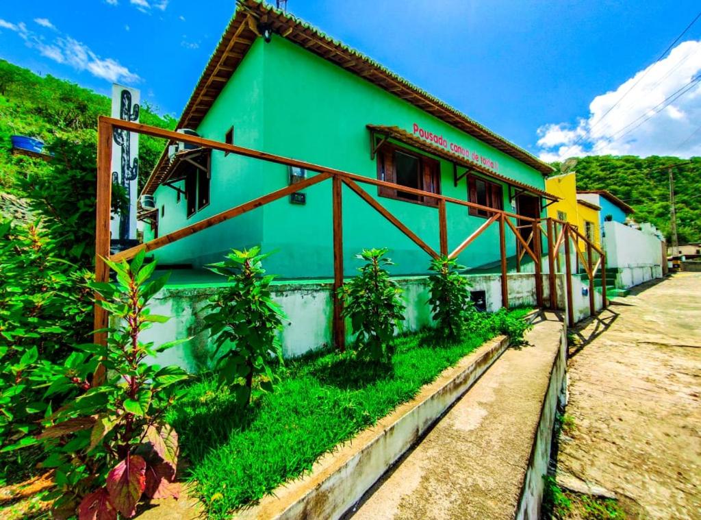 ein grünes und weißes Haus neben einer Straße in der Unterkunft Pousada Canoa de Tolda II in Piranhas