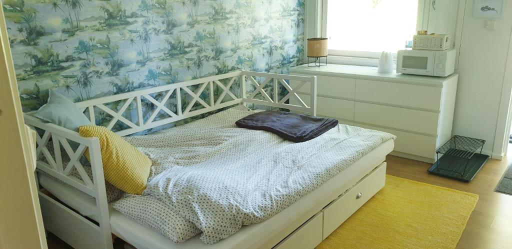 a small white bed in a room with a window at Sydåbacka Guest House, a Room with a Sauna in Kirkkonummi