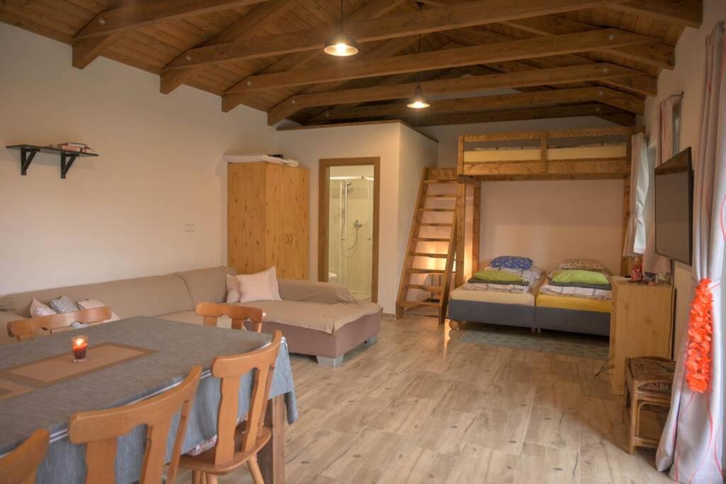 un soggiorno con tavolo, divano e letto di Útulný domek v zahradě v Unhošti nedaleko letiště a Unhošť