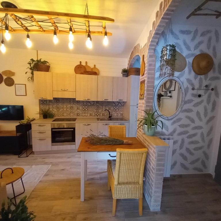 kuchnia z białymi szafkami, stołem i krzesłami w obiekcie Casa Fiorita 22 Porto Ceresio w mieście Porto Ceresio