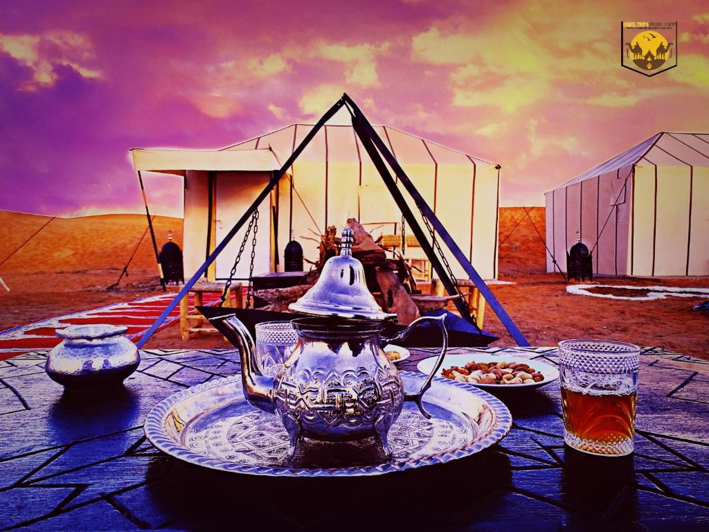 a vase sitting on a plate on a table with a tea set at Camel Trips Luxury Camp in Merzouga