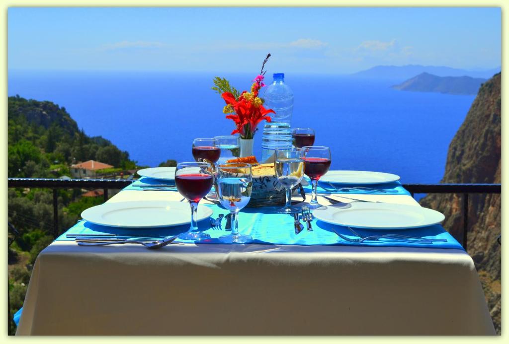 a table with glasses of wine and a view of the ocean at Keyif Motel in Faralya