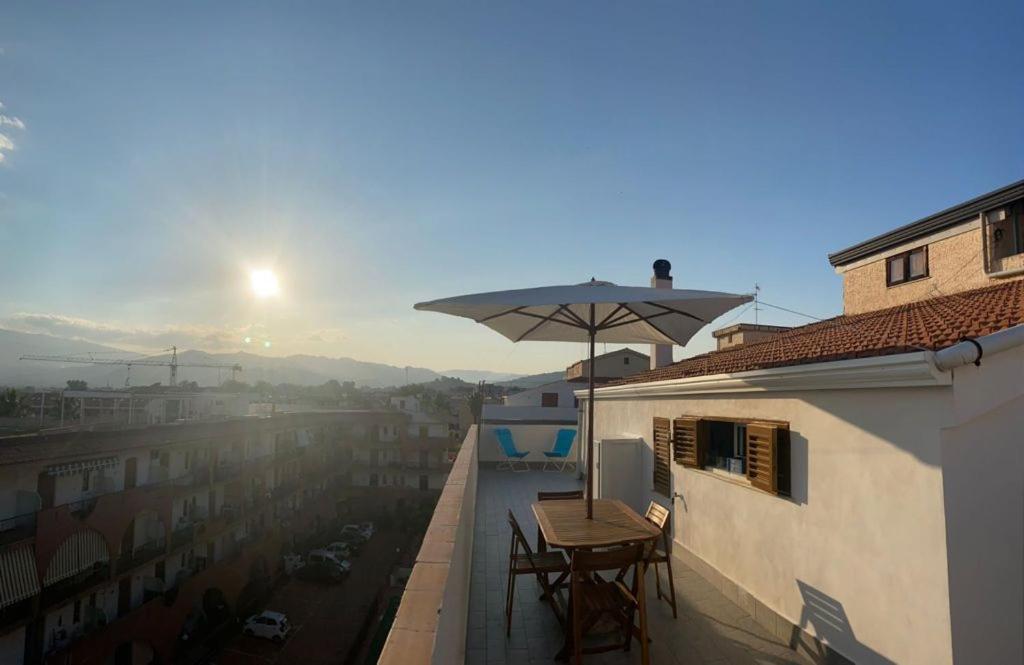 - un balcon avec deux tables et un parasol dans un bâtiment dans l'établissement BeDa House, à Giardini Naxos