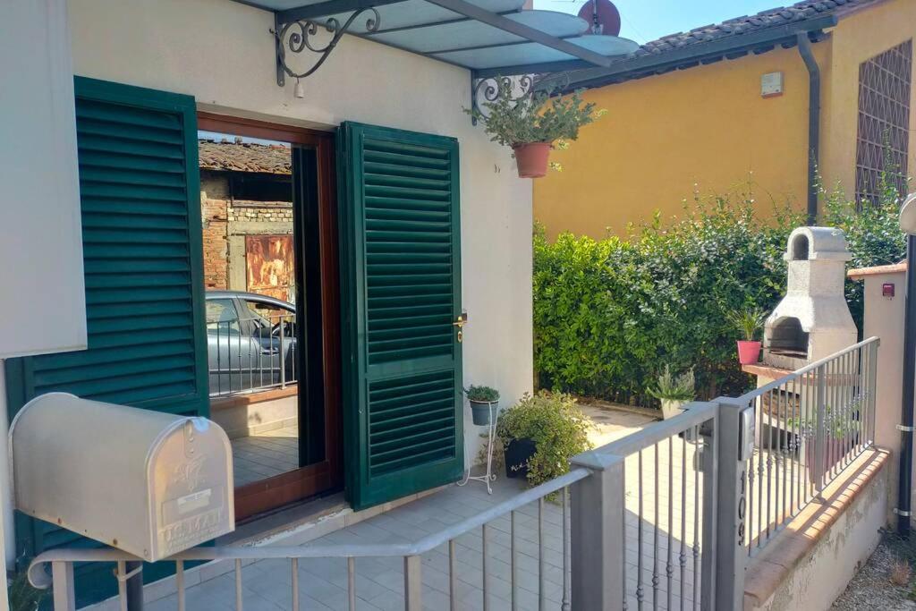 ein Haus mit grünen Türen und einem Zaun in der Unterkunft Poggio ai Grilli Apartment in Certaldo