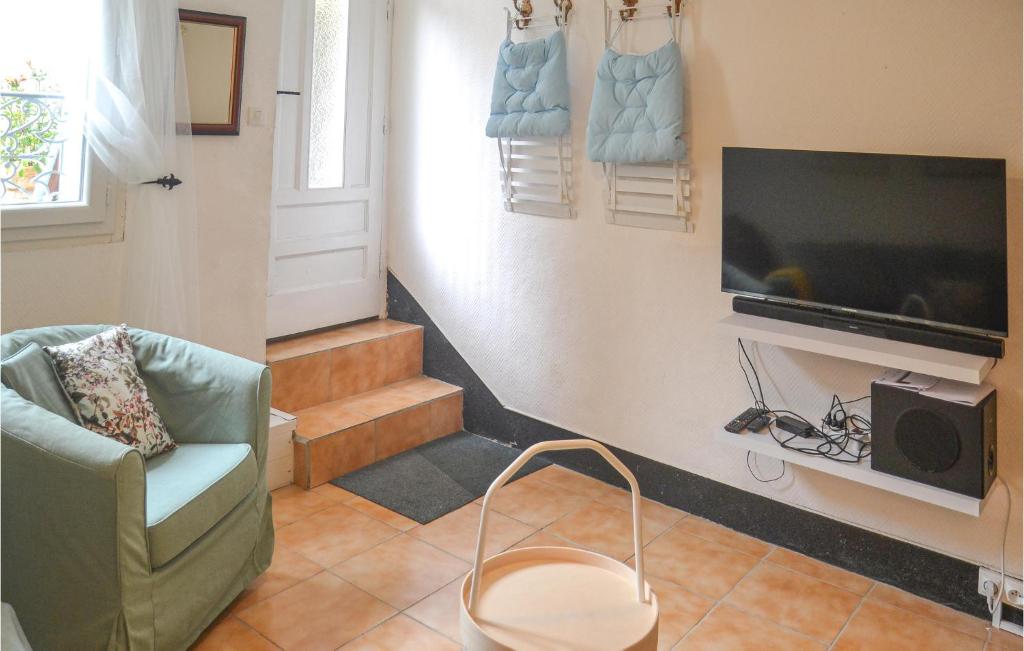 ein Wohnzimmer mit einem TV und einem Stuhl in der Unterkunft 2 Bedroom Nice Home In Saint-gervais-sur-mare in Saint-Gervais-sur-Mare