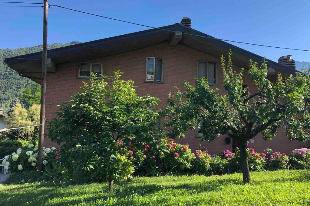 a red brick house with trees and flowers in the yard at La Maison des Hirondelles Alloggio ad uso turistico - VDA SAINT-PIERRE 0035 in Saint-Pierre