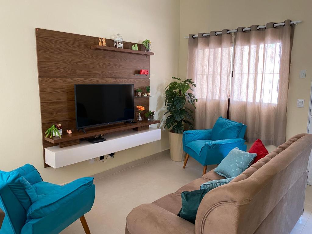 een woonkamer met twee blauwe stoelen en een televisie bij Casa em Brotas, Refúgio e Aconchego in Brotas