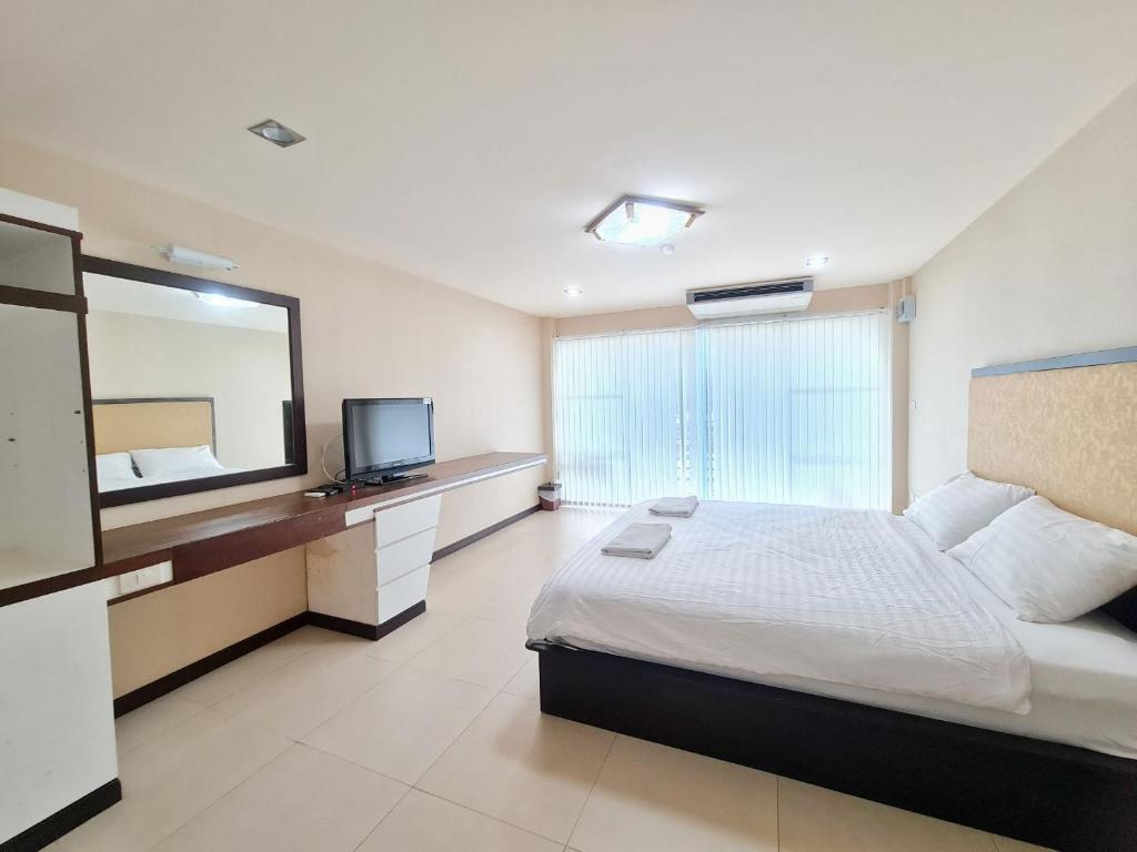 a bedroom with a large bed and a television at โรงแรม ชาโตว์วิสต้า in Chon Buri