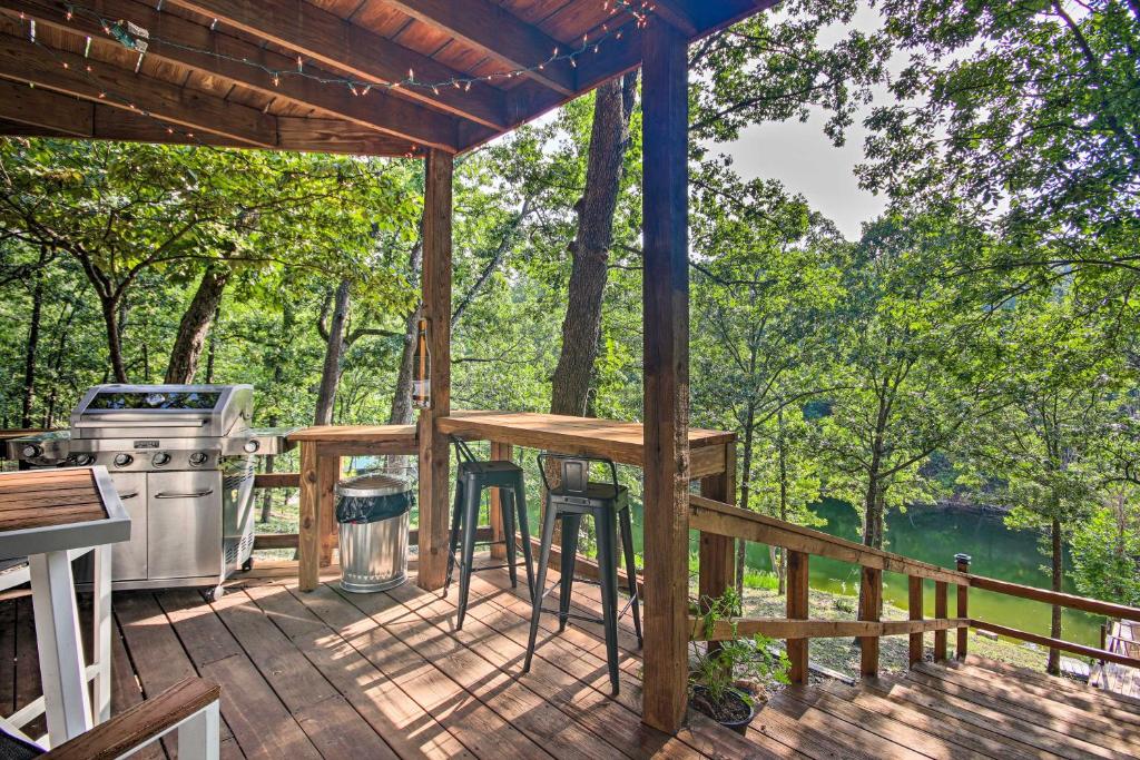 a screened in porch with a grill and a table at Stylish Grand Lake Retreat with Fishing Dock! in Eucha