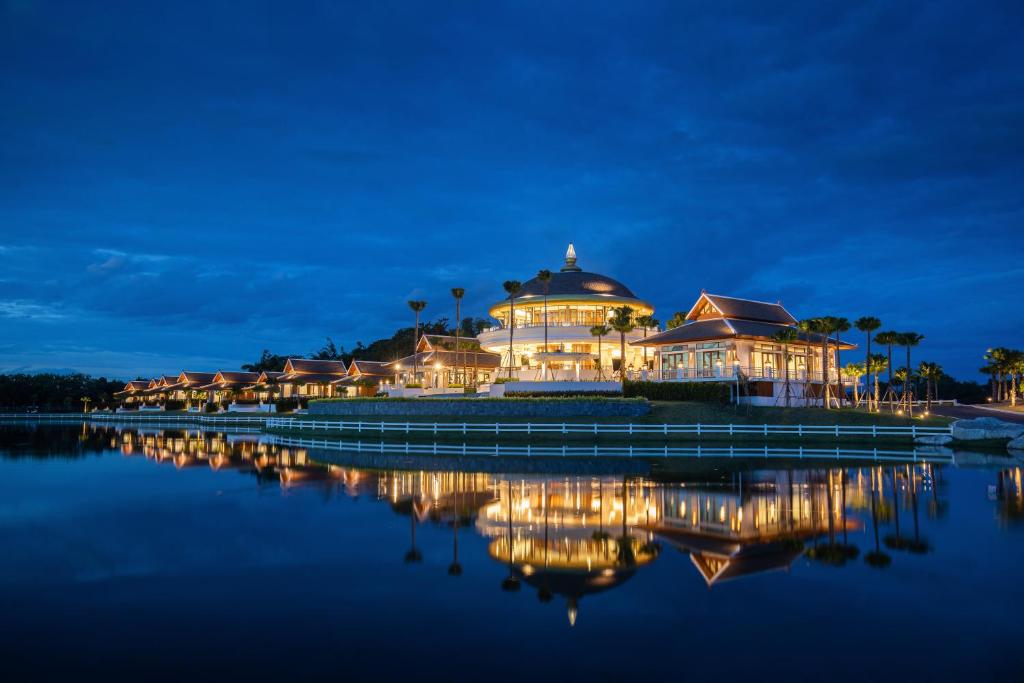 チェンマイにあるThantara Resort Chiang Maiの夜間の水面灯が灯る大きな建物