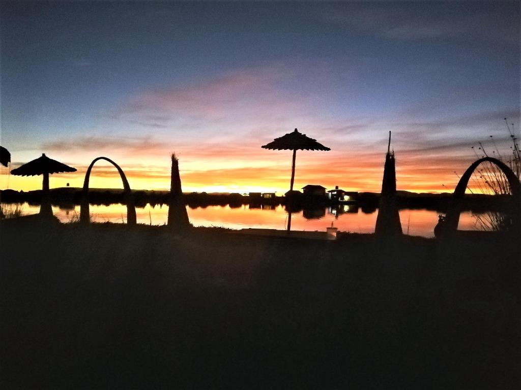 un coucher de soleil sur une étendue d'eau avec des parasols dans l'établissement Room in Lodge - Lucsay Titicaca Lodge, à Puno