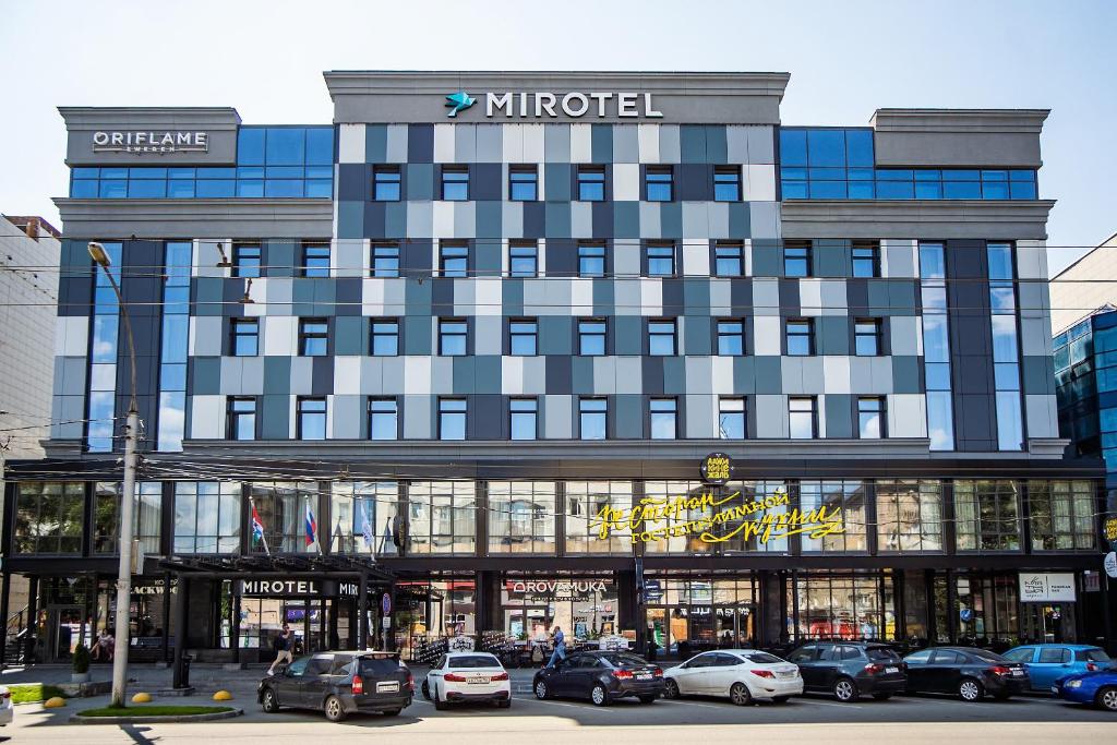 a large building with cars parked in front of it at Mirotel Novosibirsk in Novosibirsk