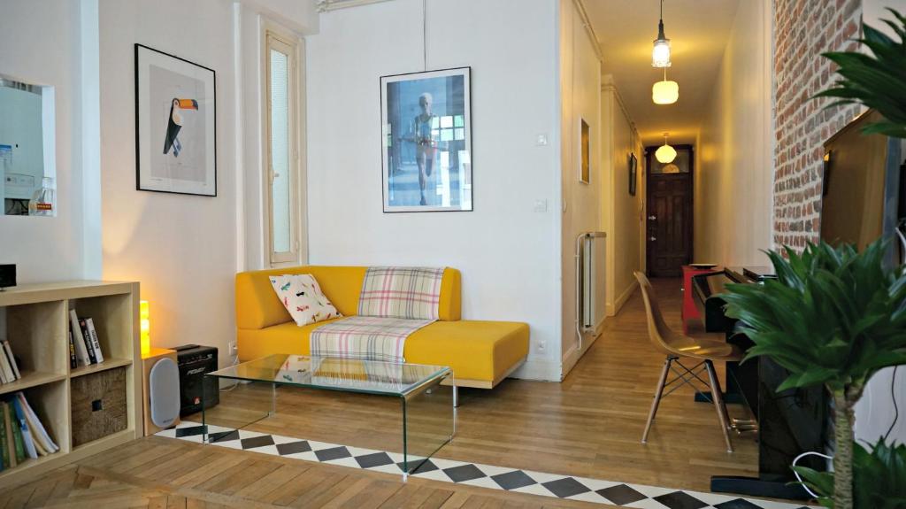 a living room with a yellow couch and a coffee table at Little Suite - Marianne in Lille