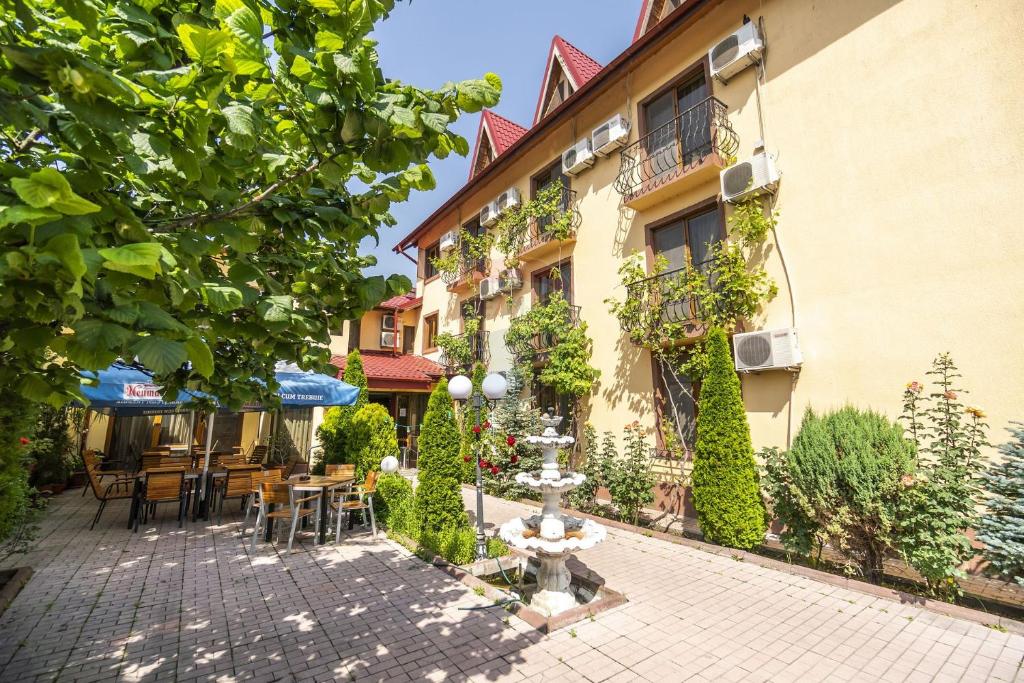 a courtyard of a building with tables and chairs at Hotel SYM in Ploieşti