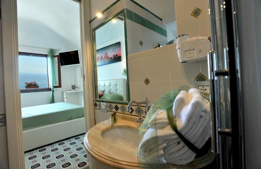bagno con vasca e lavandino con specchio di World Center ad Amalfi