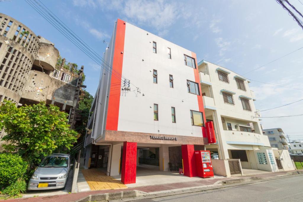 a building with a red and white facade on a street at Terrace Resort 8 in Ginowan