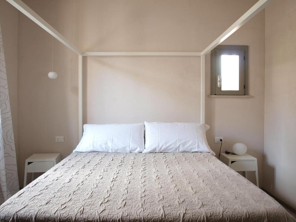 a bedroom with a bed with white sheets and a window at Casa vacanze "Officina del fabbro" - Menfi in Menfi