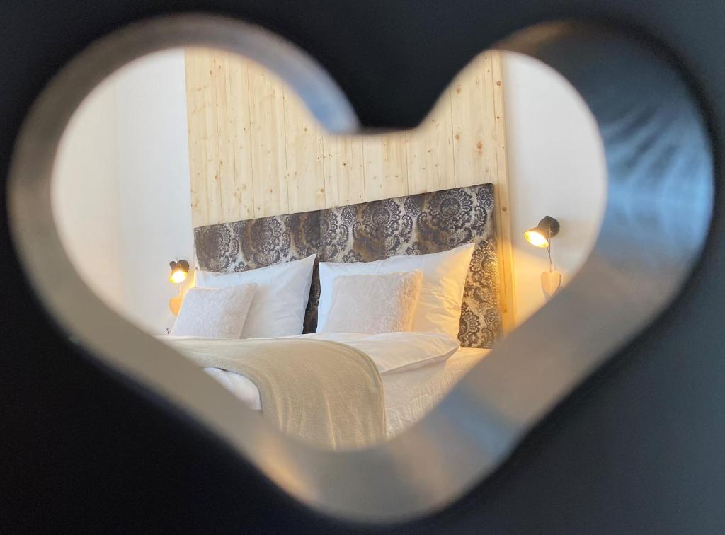 a view of a bed through a heart shaped window at Alpine Chalet Aurora Dolomites in Laion