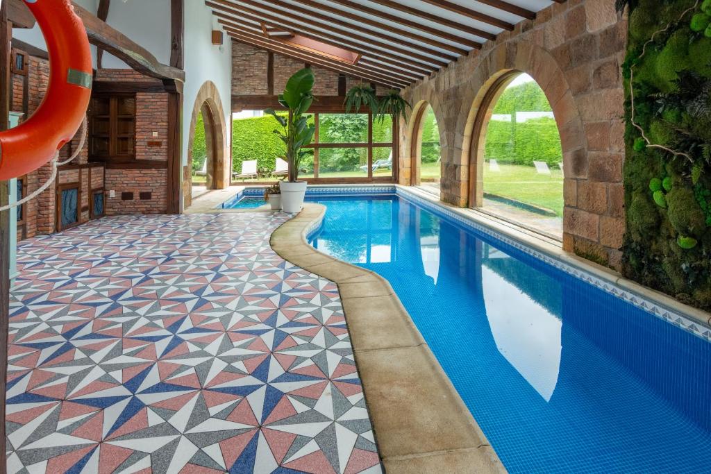 an indoor swimming pool with a tile floor and a swimming slide at Luxury Villa Esmeralda in Suances