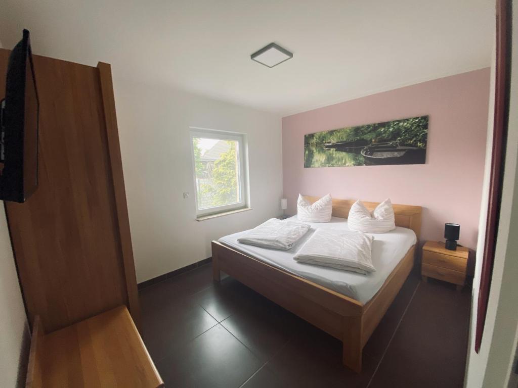 ein Schlafzimmer mit einem Bett mit weißen Kissen und einem Fenster in der Unterkunft Spreewaldferienhäuser am Deich in Lübben