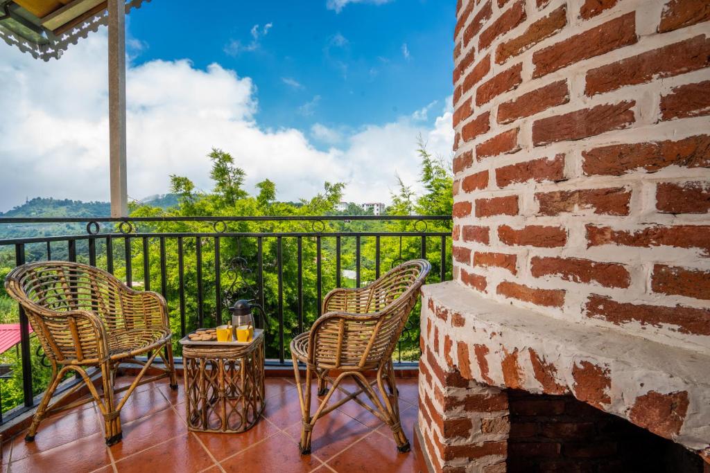 a balcony with chairs and a brick wall at Cottages @ Village in Bhīm Tāl