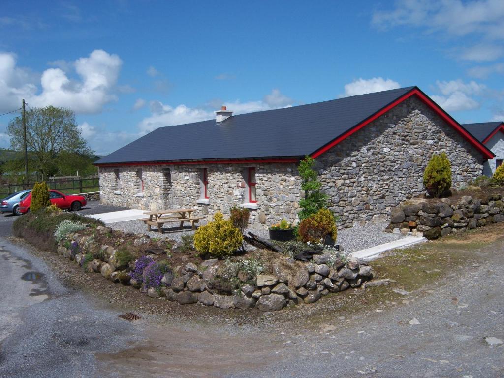 a large stone building with a stone wall at Valley Lodge Farm Hostel in Claremorris