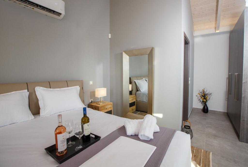 1 dormitorio con 1 cama y bandeja de botellas de vino en Théa boutique villas sivota II, en Sivota