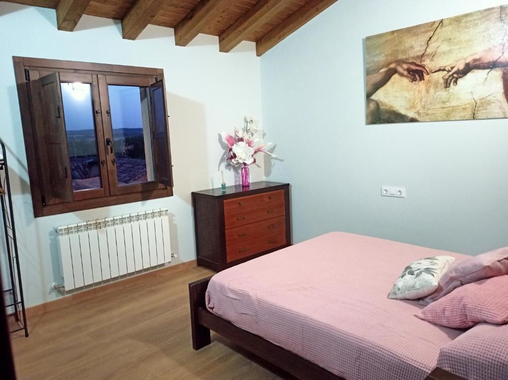 a bedroom with a bed and a dresser and a window at Casa Rural El Mirador de San Miguel in San Esteban de Gormaz