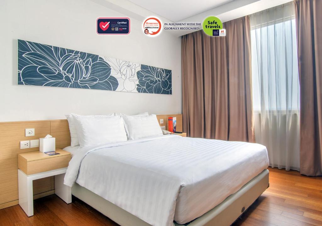 a bedroom with a large white bed and a window at Swiss-Belinn Airport Jakarta in Tangerang