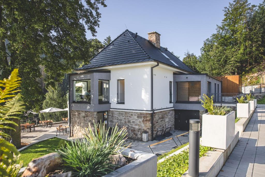 a small white house with a black roof at Forest Resort in Vír