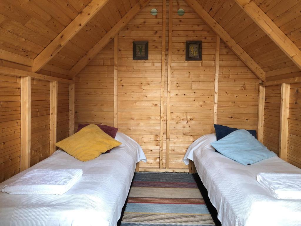 2 Betten in einer Hütte mit Holzwänden in der Unterkunft Ollilan tupa Joensuun lähellä in Ylämylly
