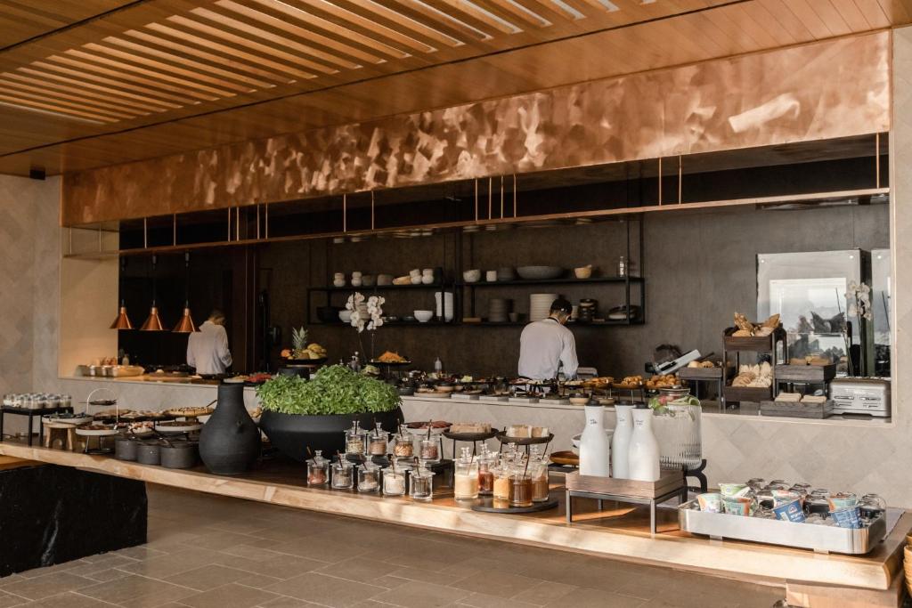 a restaurant kitchen with a counter with people preparing food at Acro Suites - A Wellbeing Resort in Agia Pelagia
