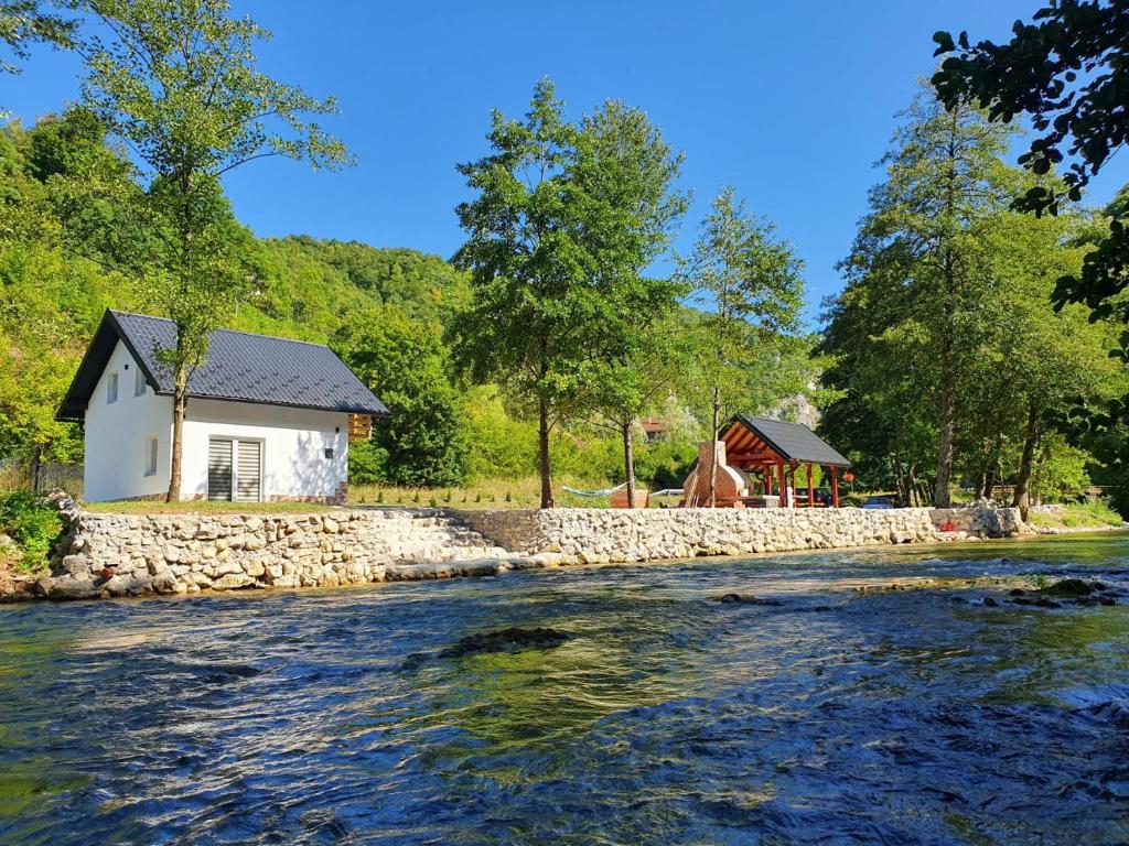 ein Haus neben einem Fluss mit einer Steinmauer in der Unterkunft Otoka Josikovic in Šipovo