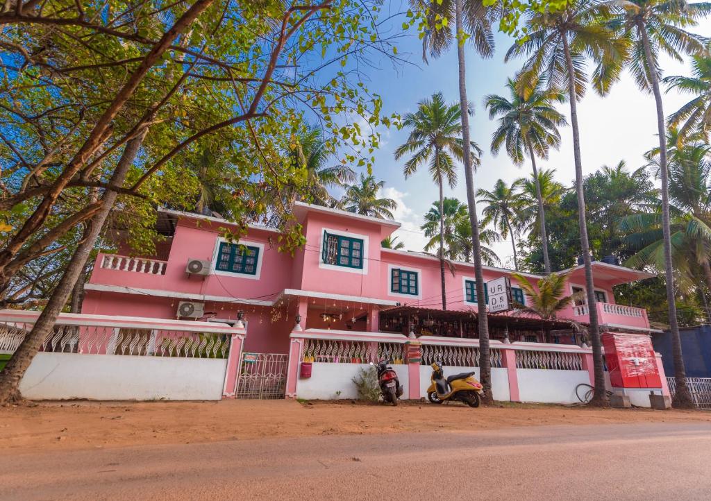 una casa rosa con una moto aparcada delante de ella en U.R.D.Ki Hostel, en Anjuna