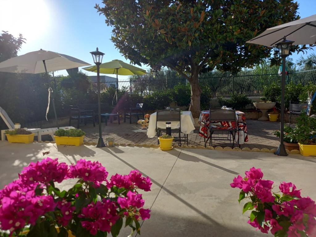 a patio with pink flowers and tables and umbrellas at IRIS COTTAGE b&b in Campomarino
