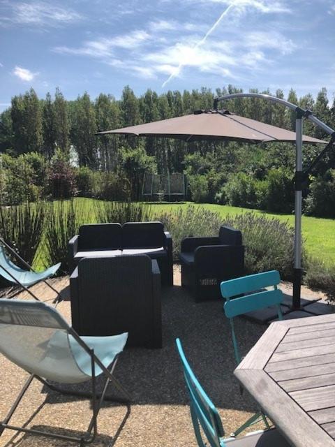 a patio with chairs and a table and an umbrella at Kervran in Plouhinec