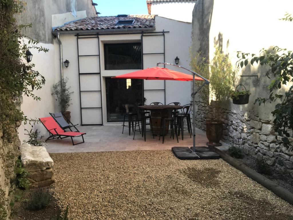 eine Terrasse mit einem Tisch und einem roten Regenschirm in der Unterkunft La Bourgade in Céreste