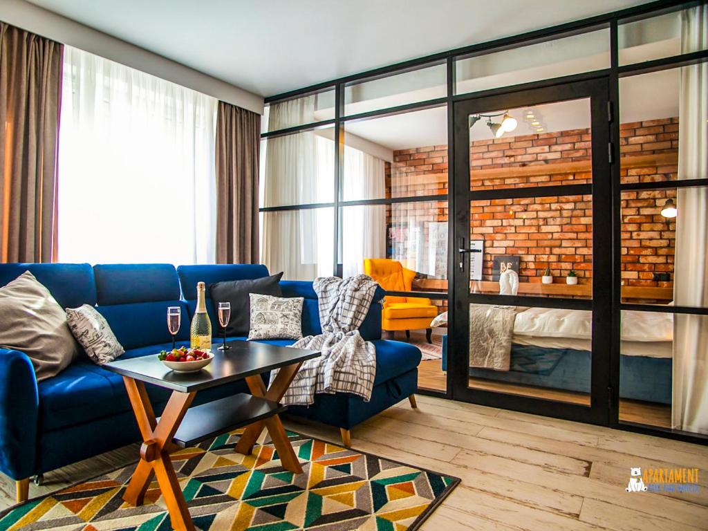 a living room with a blue couch and a table at Apartament Park nad Hańczą in Suwałki