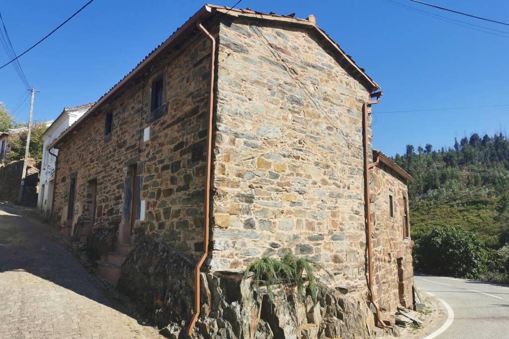 an old brick building on the side of a street at Casa do Linho 400 year old country cottage in Oleiros