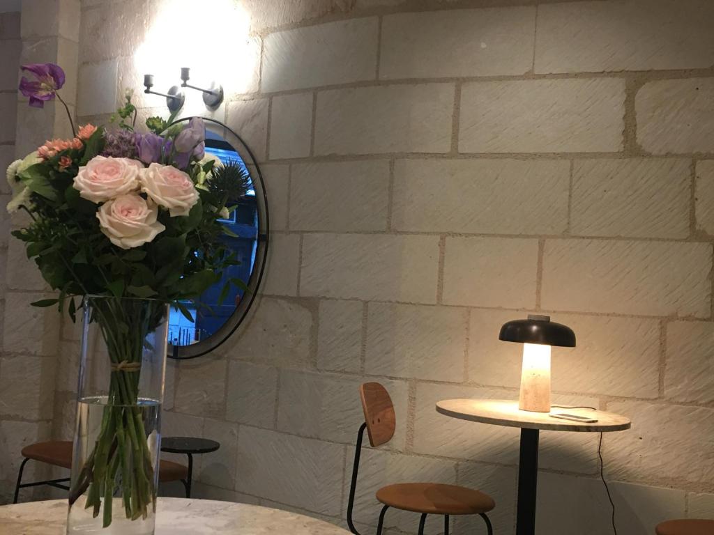 a table topped with a vase filled with flowers at Hôtel L'Adresse in Tours