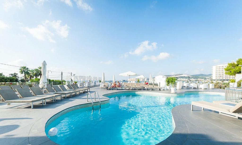 una piscina con tumbonas y un hotel en Typic Marina Playa - Adults Only en Bahía de San Antonio