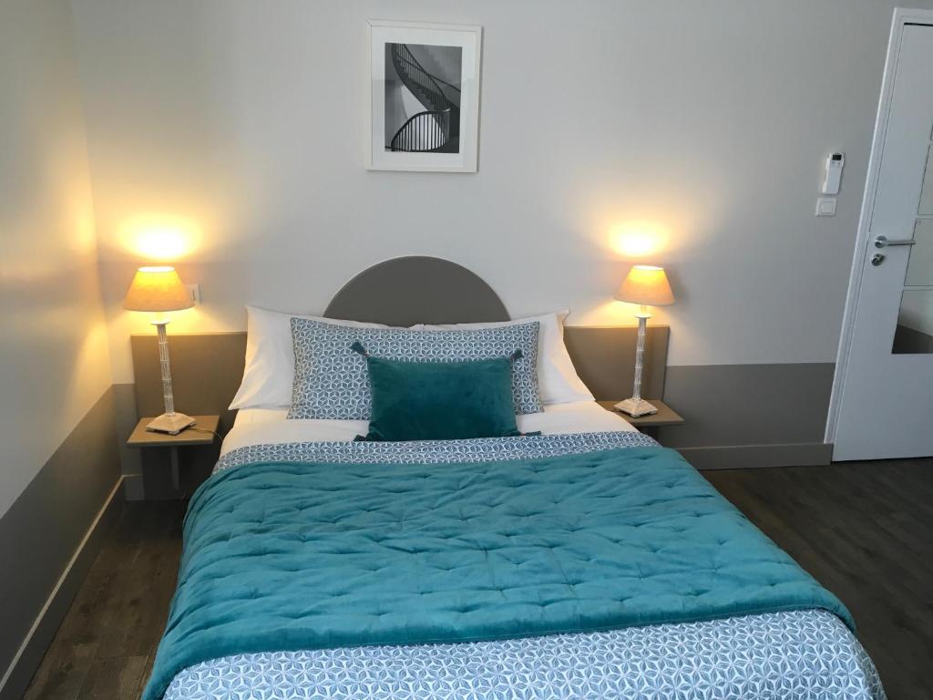 a bedroom with a large bed with blue sheets and two lamps at Hôtel L'Adresse in Tours