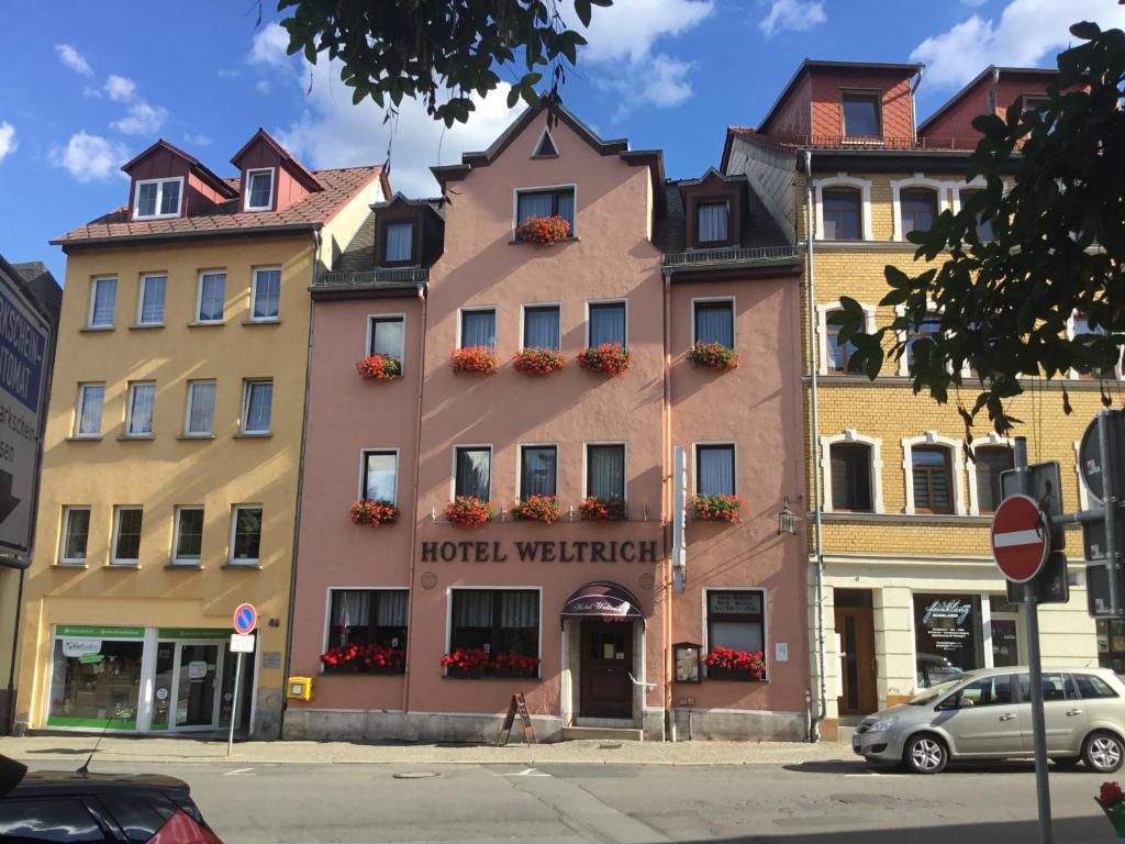 ein hoteloren-Gebäude in einer Stadtstraße mit parkenden Autos in der Unterkunft Hotel Weltrich in Saalfeld