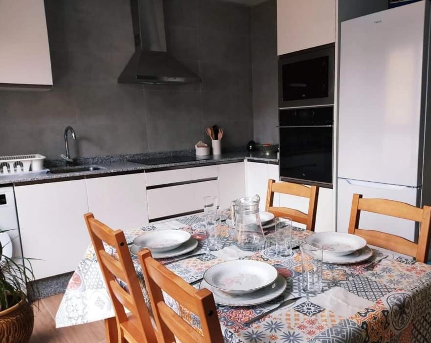 una cocina con una mesa con platos y vasos. en A Apartamentos Diego, en O Grove