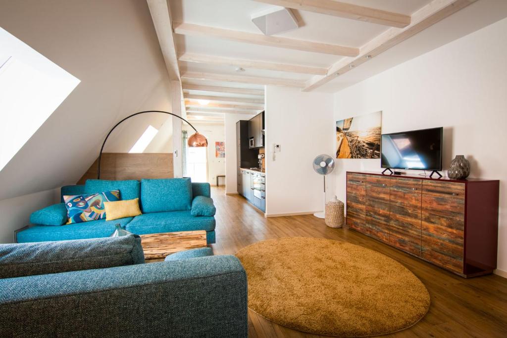 a living room with a blue couch and a tv at Stadtapartments Forchheim in Forchheim