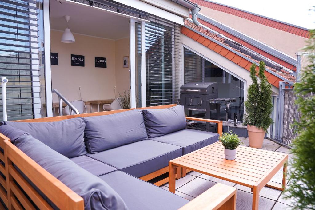une terrasse avec un canapé, une table et un grill dans l'établissement FullHouse - Halle - AB7 rooftop - BBQ Grill - Elevator - Balcony, à Halle-sur-Saale