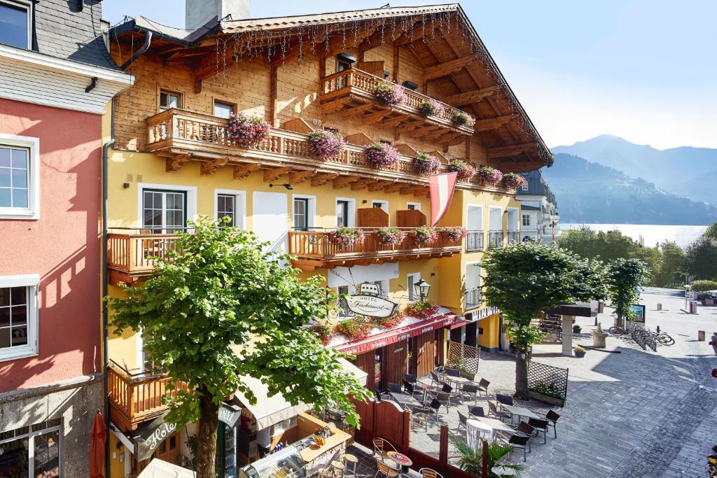 un edificio con balcones, mesas y sillas en Fish'Inn Zell - Hotel Fischerwirt, en Zell am See